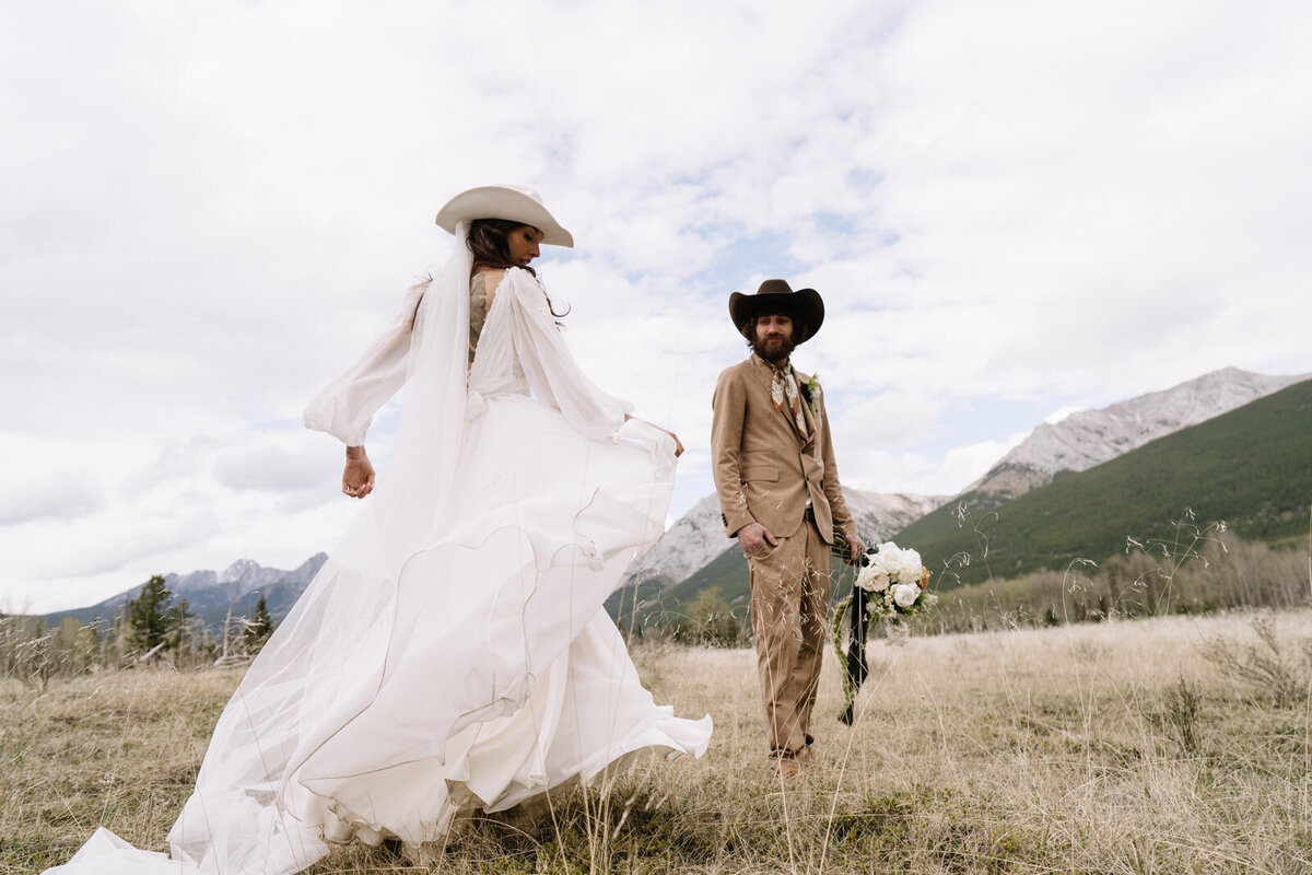 Bride and groom wearing hats in the mountains — editorial destination wedding portrait blending romance, adventure, and effortless style.