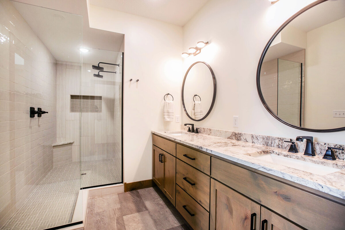 Custom bathroom with dark cabinets, double vanity, and walk-in shower in Elk River custom home