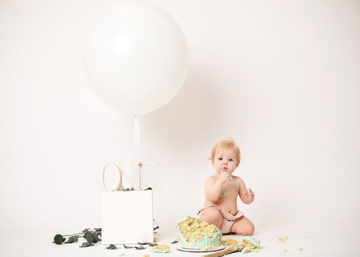All white cake smash photoshoot with baby eating cake by Los Angeles Photographer