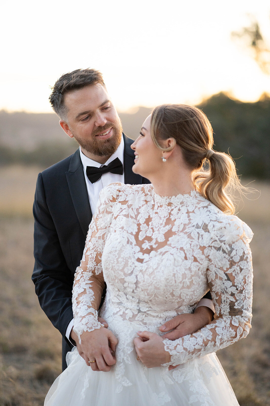 Bride and groom embracing at sunset in a scenic outdoor setting