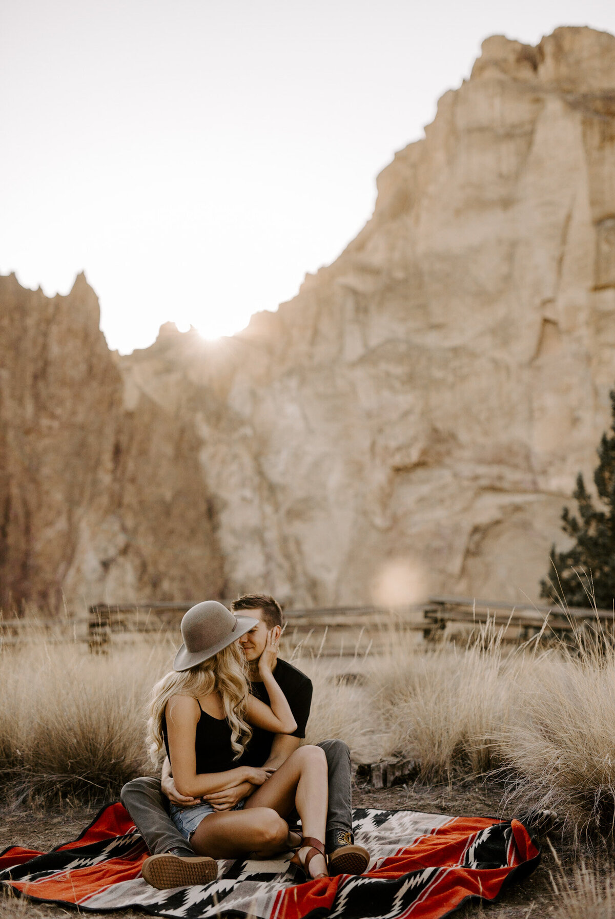 Couple sits on a blanket together in front of Smith Rock