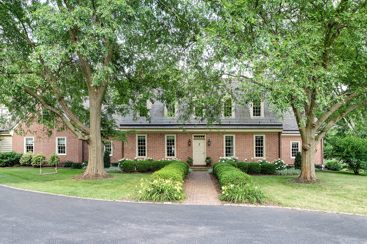 brick house exterior with entryway garden and two tall trees