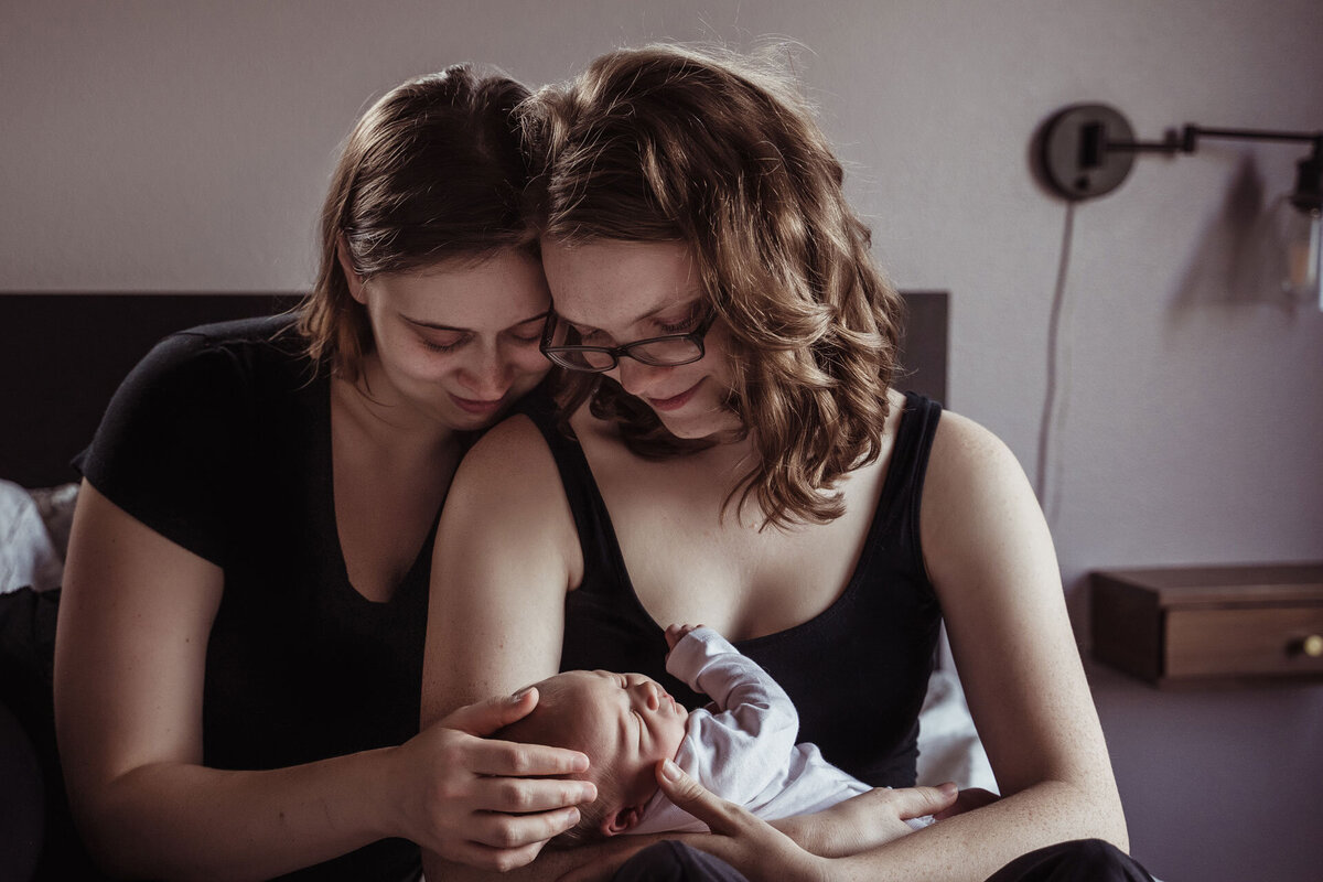 two lesbian mothers cradle their newborn