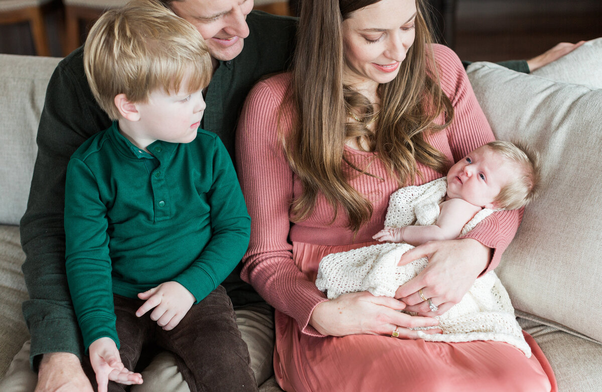 a family holding their new baby with a toddler during an at-home newborn session
