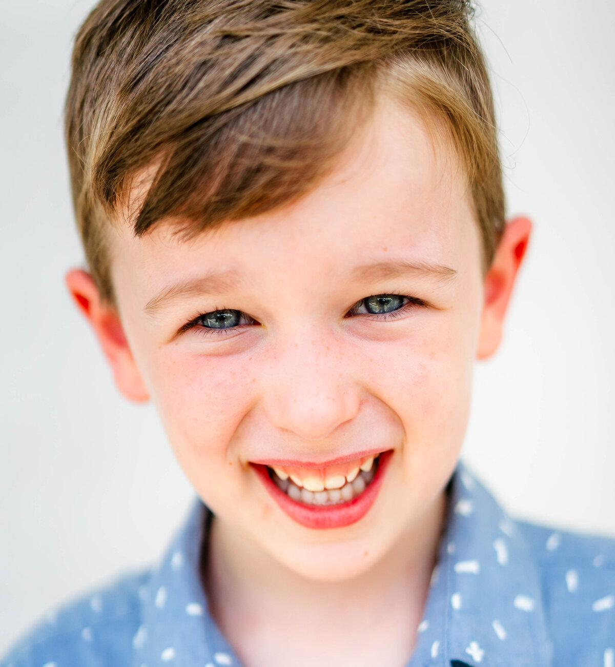 Boy with short hair and natural grin, fine art school photo on white background