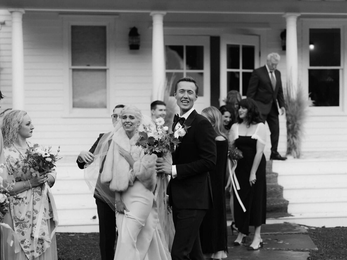 The bride and groom, with some guests, are outside the Foxfire Mountain House, New York. Wedding Image by Jenny Fu Studio