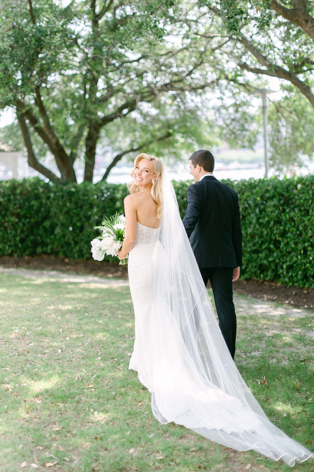 A bride smiles over her shoulder while following her groom.
