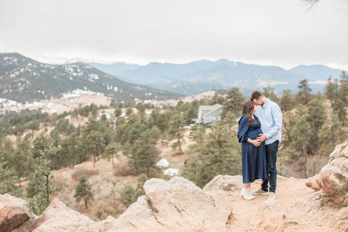 A couple during their maternity session with a mountain view overlooking Denver