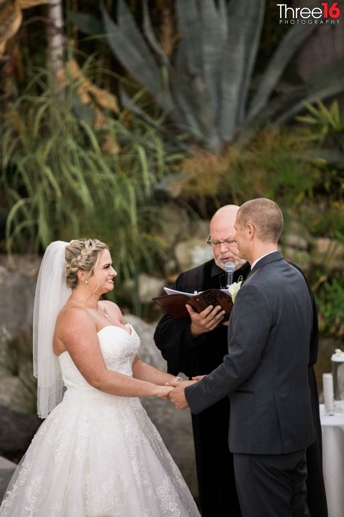 Bride and Groom hold hands as they face each other while the officiant reads off the vows