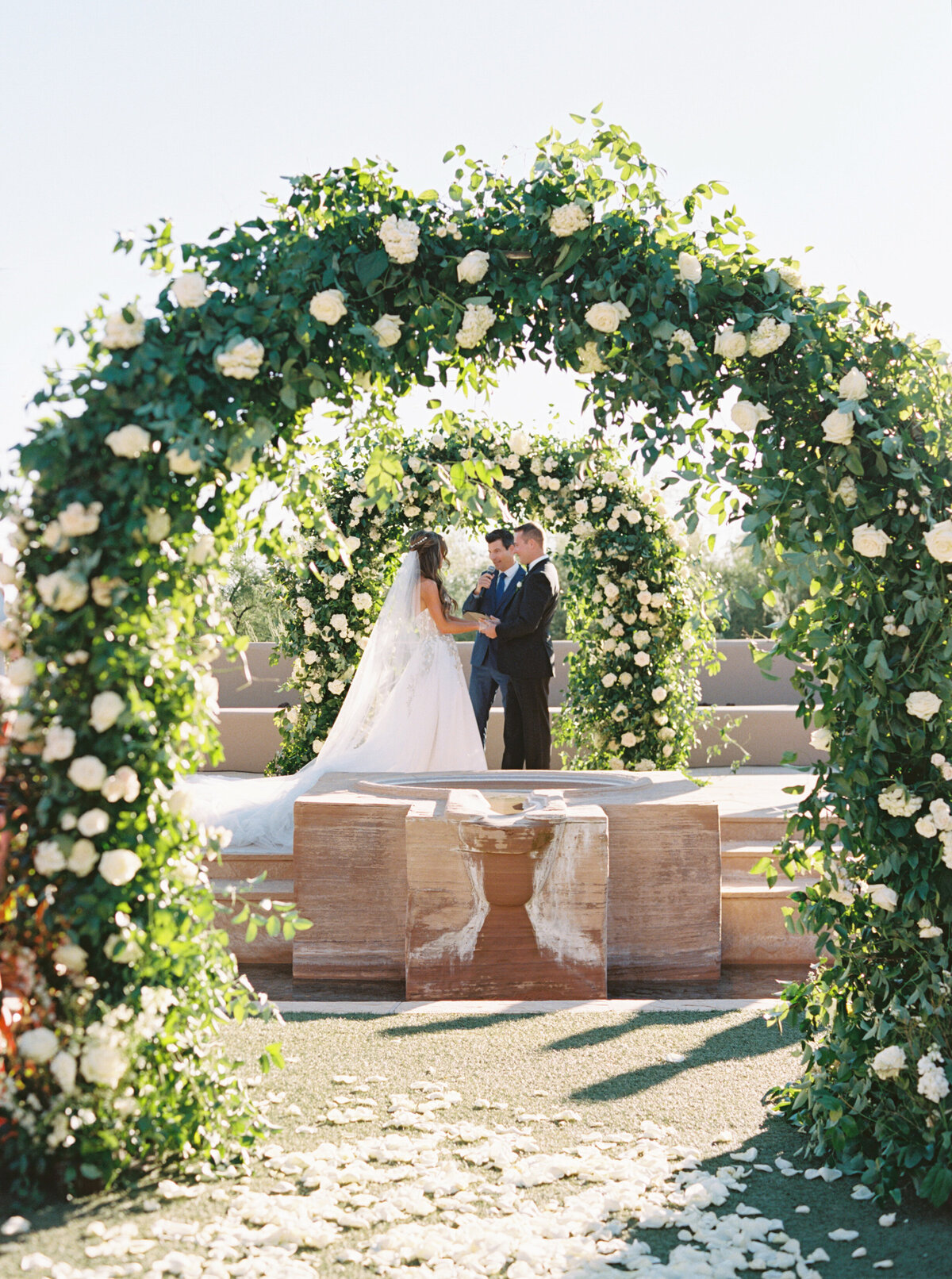 A beautifully designed floral arch creates the perfect backdrop for a romantic wedding ceremony under the open sky.