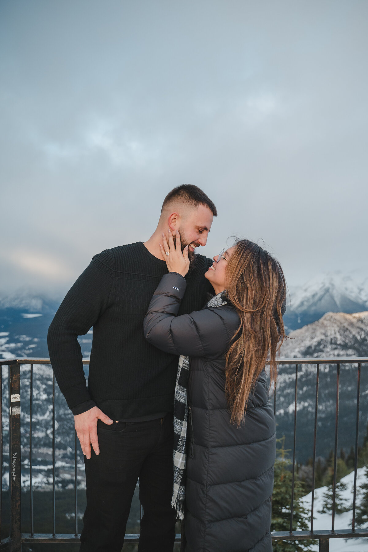 Couple smiling on Banff viewpoint at Sulphur Mountain with mountains in background.