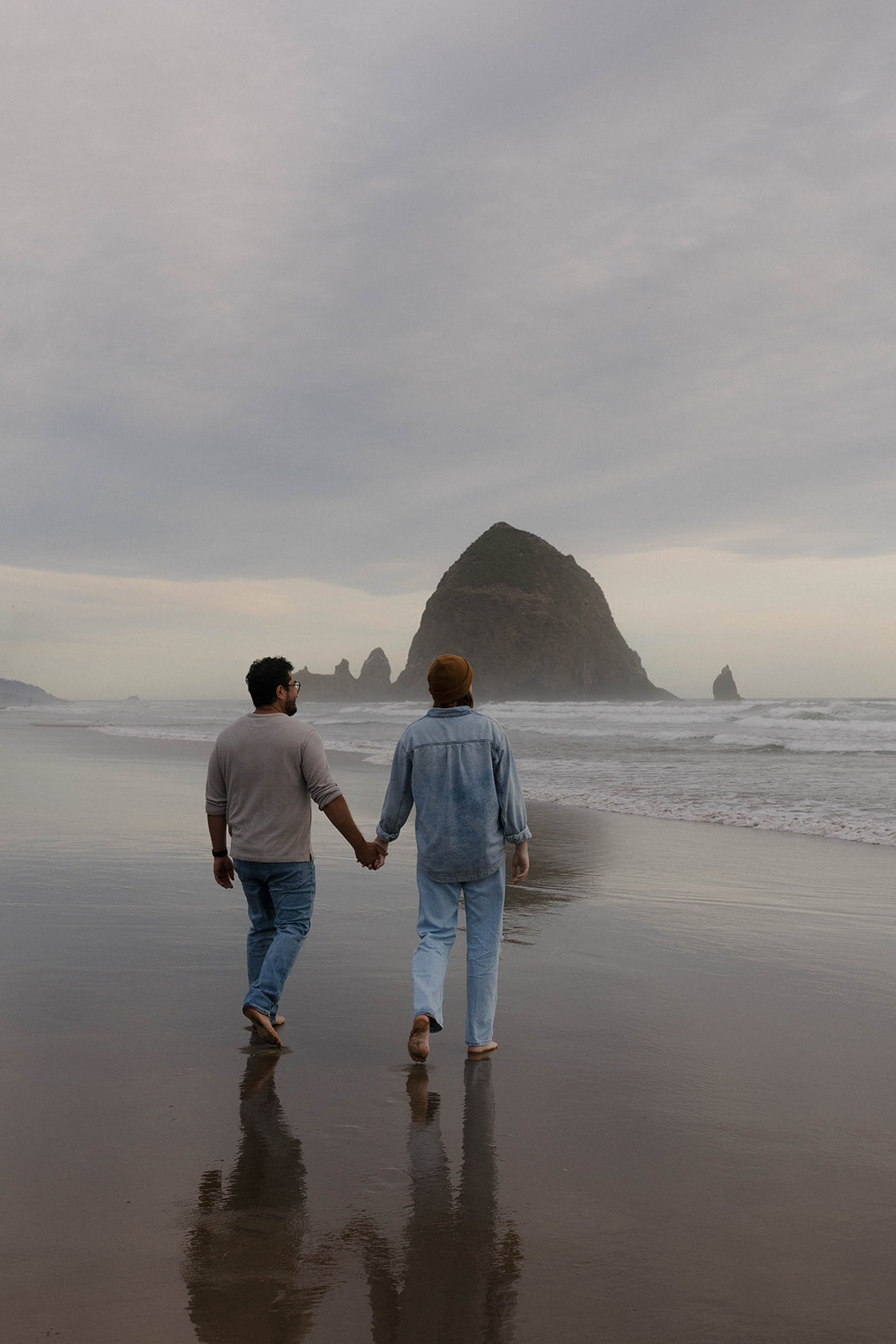 A couple holding hands on the Oregon coast, showcasing a cinematic and documentary wedding photography style.