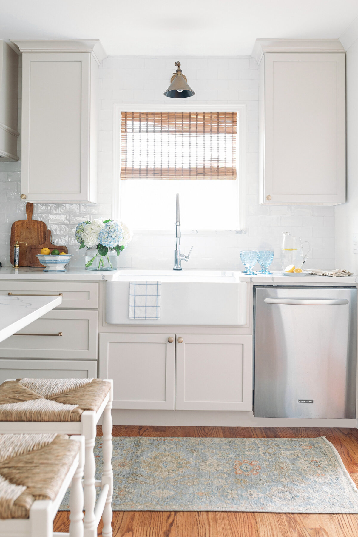 Fresh traditional kitchen renovation and white porcelain sink with window above and bamboo shades