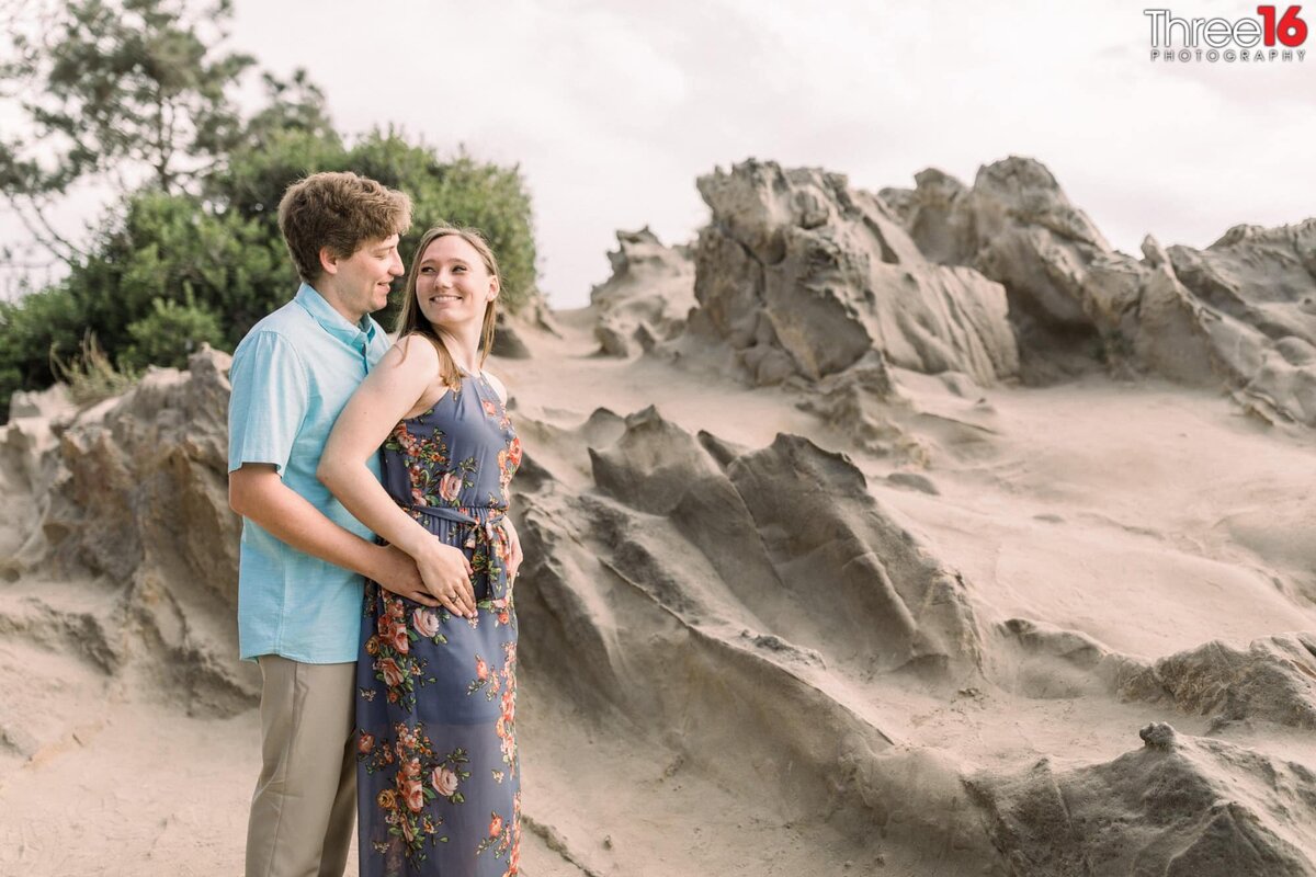 Bride to be looks back at her Groom amongst the rock formations at Corona del Mar State Beach