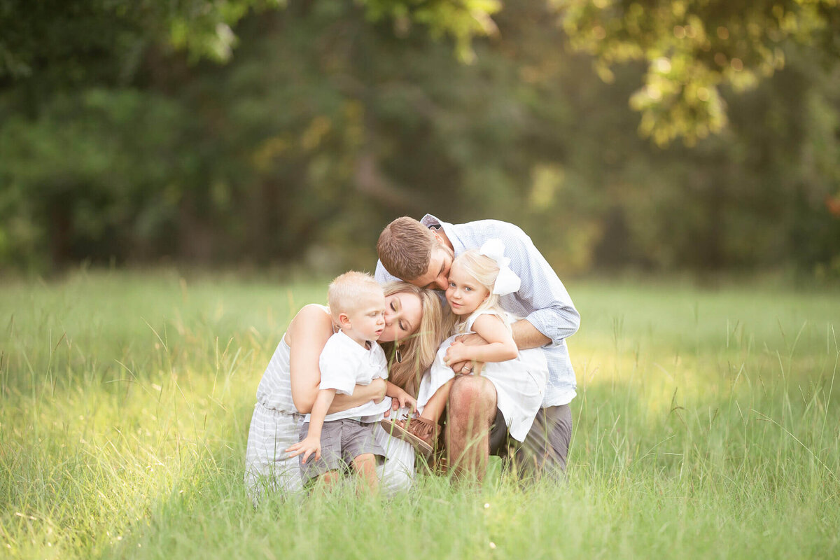 family in a field kissing each other