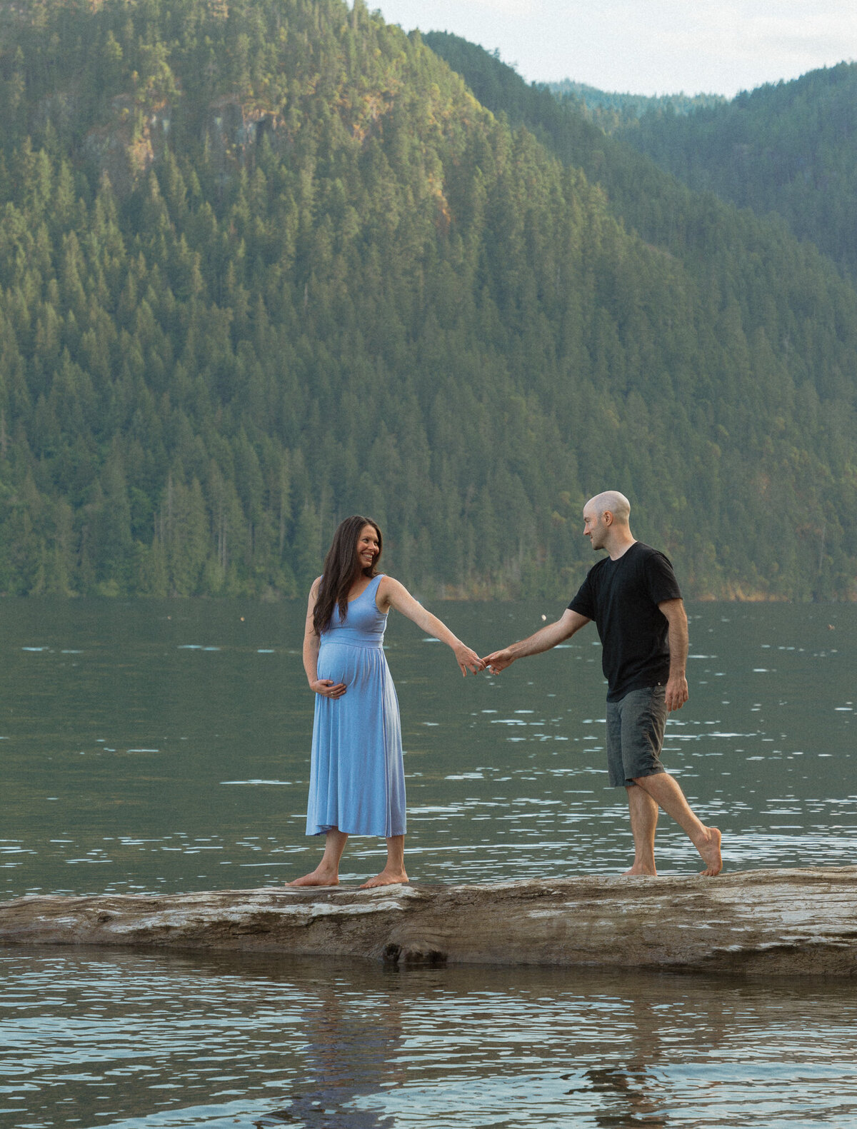 expecting parents walking on a log at Comox Lake during their maternity session by Latitude 49 Photography