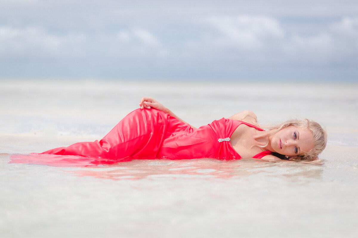 beautiful woman in pink dress laying in the water