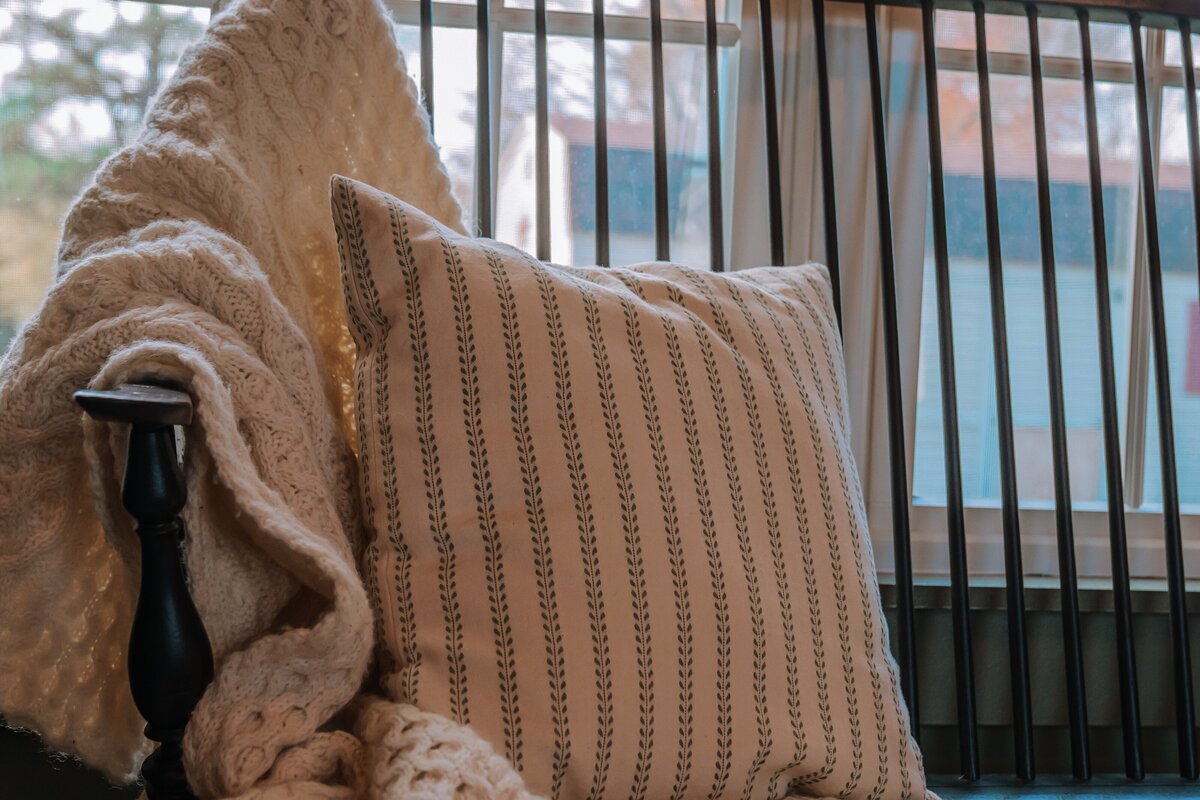 Spindle wooden double seated wooden bench with cream Irish Aran knit woolen blanket and pillow