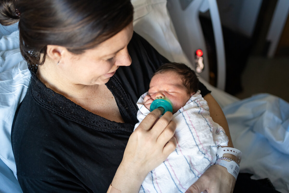 Mom snuggling baby wrapped in swaddle