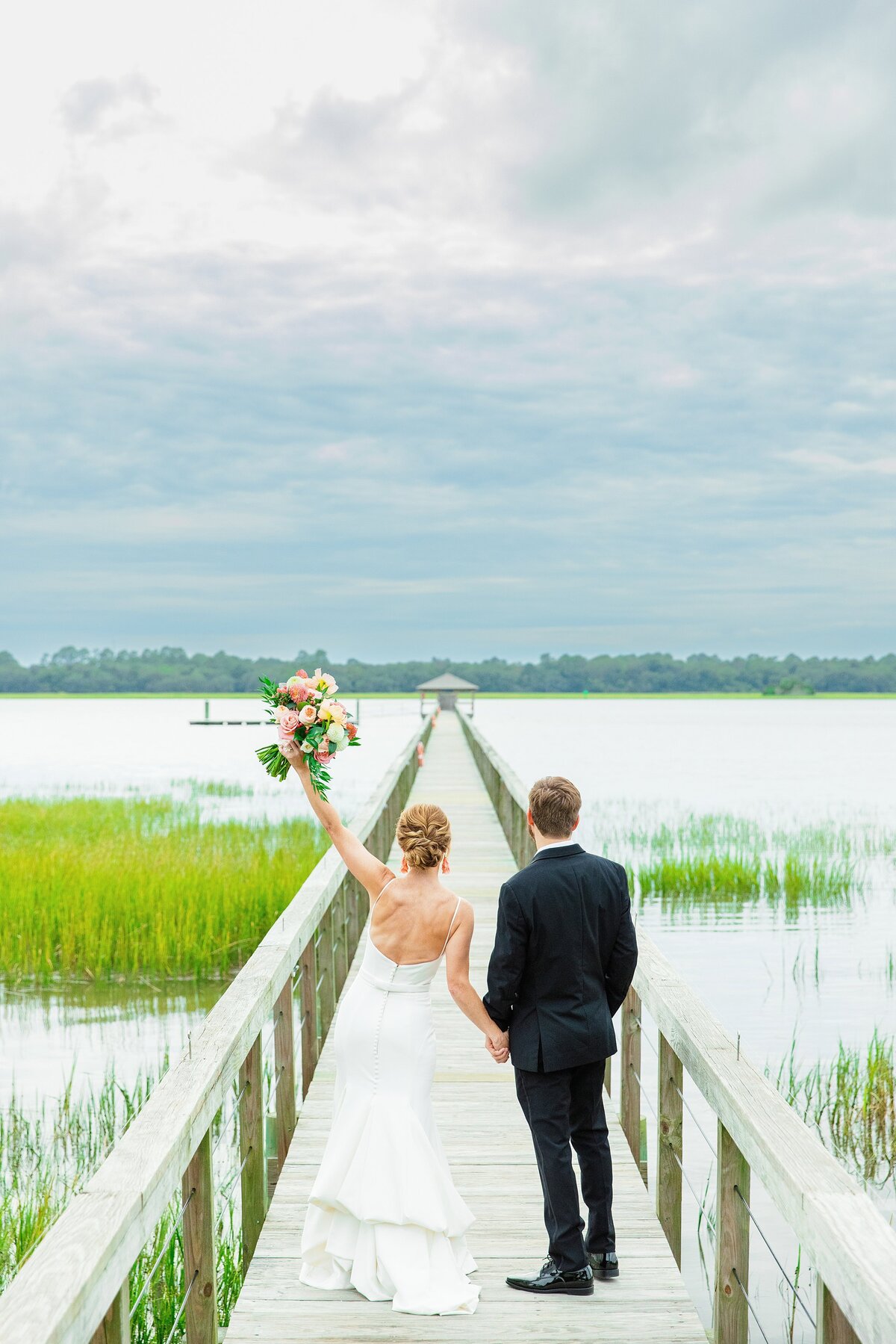 bride and groom walk out on a dock after their wedding ceremony