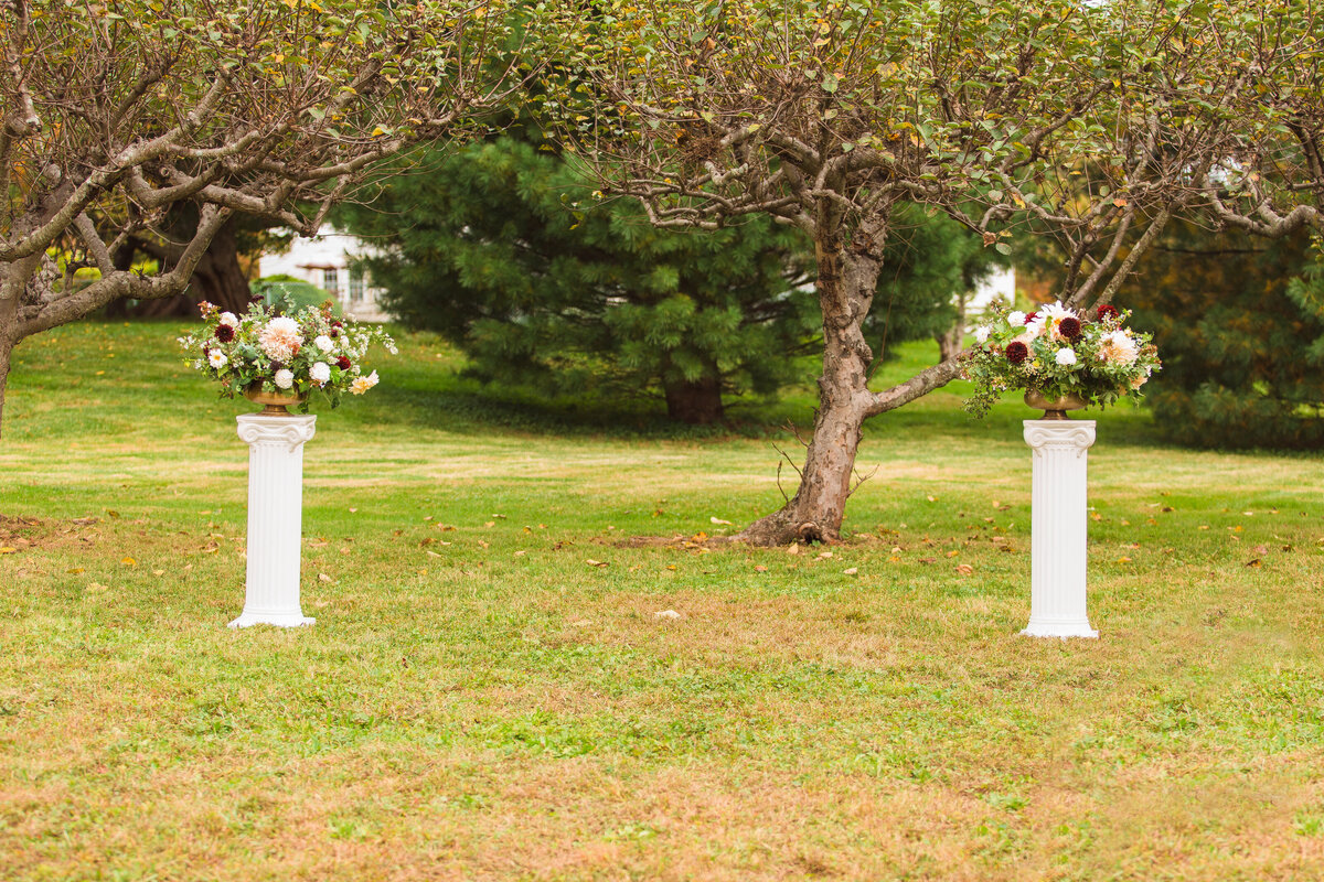 Floral pillars at orchard wedding ceremony.