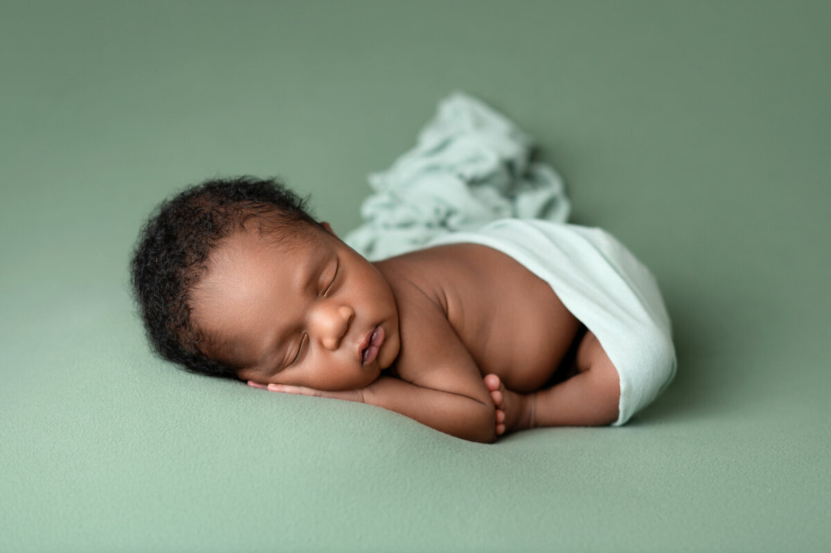 Newborn baby sleeping soundly in light green wrap – Lissette G photography.