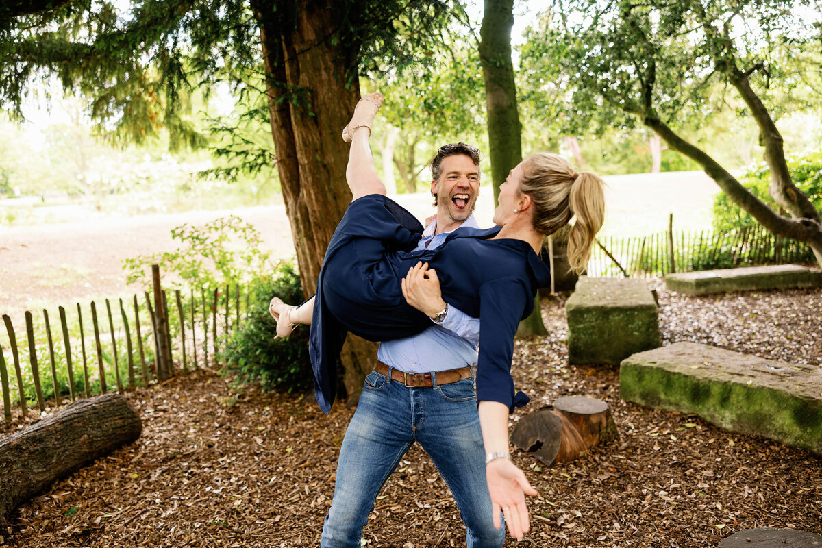 An pre wedding photo shoot image of a guy picking a girl up and spinning her around in Museum Gardens, York