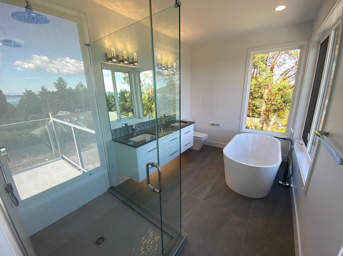 Bathroom interior design with walk-in shower, gray tile floors, freestanding tub, rainfall showerhead, white double vanity