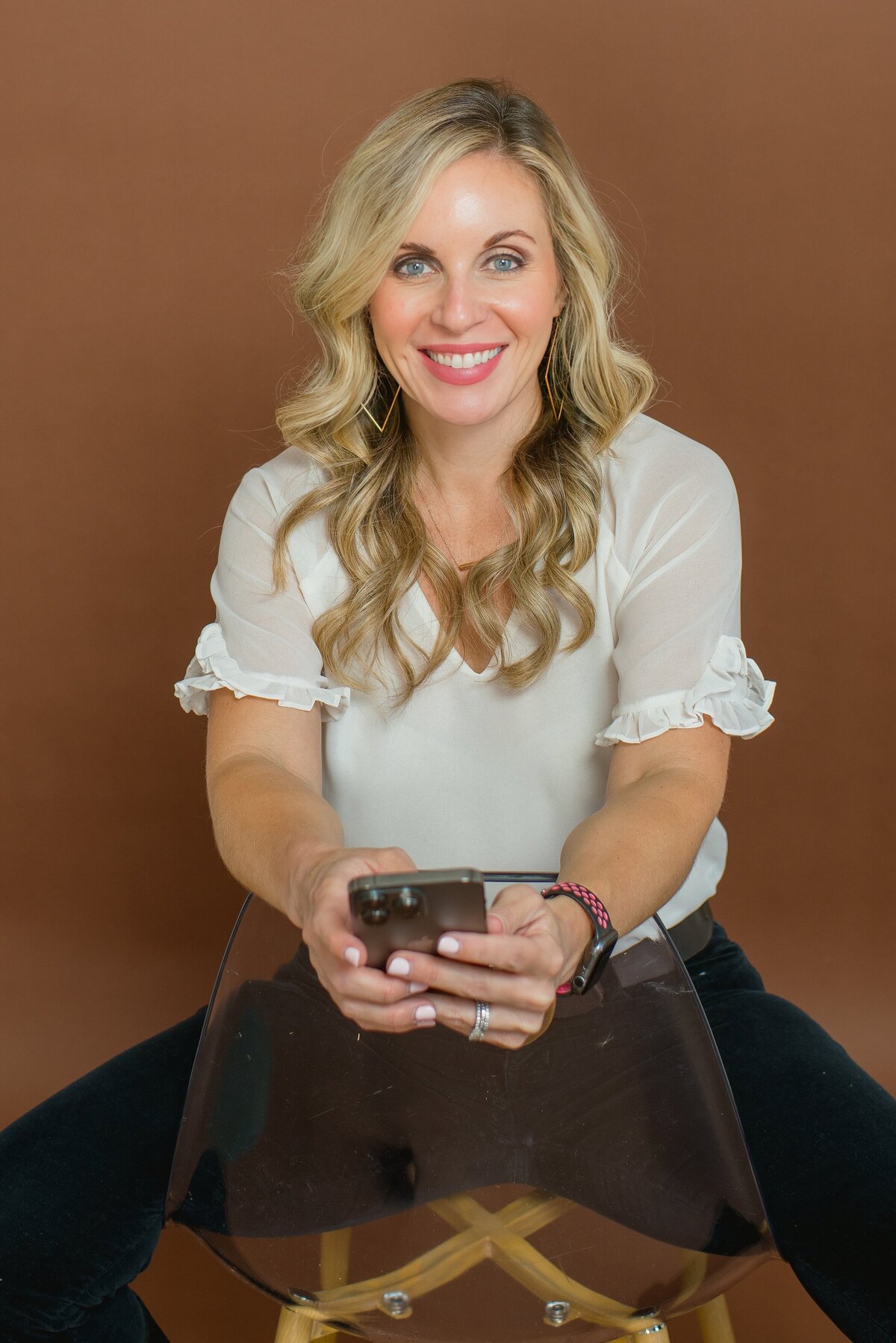 Social media manger holding her phone smilining at the camera