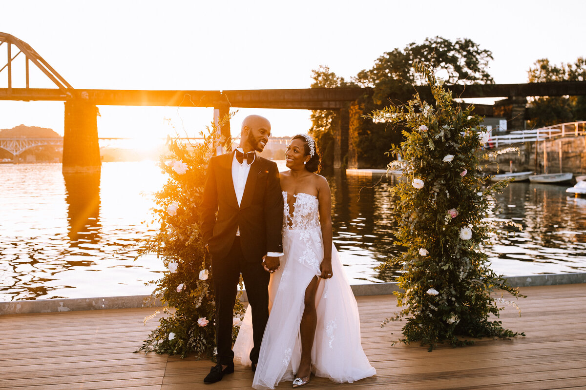 Bride and groom on a dock at sunset. 