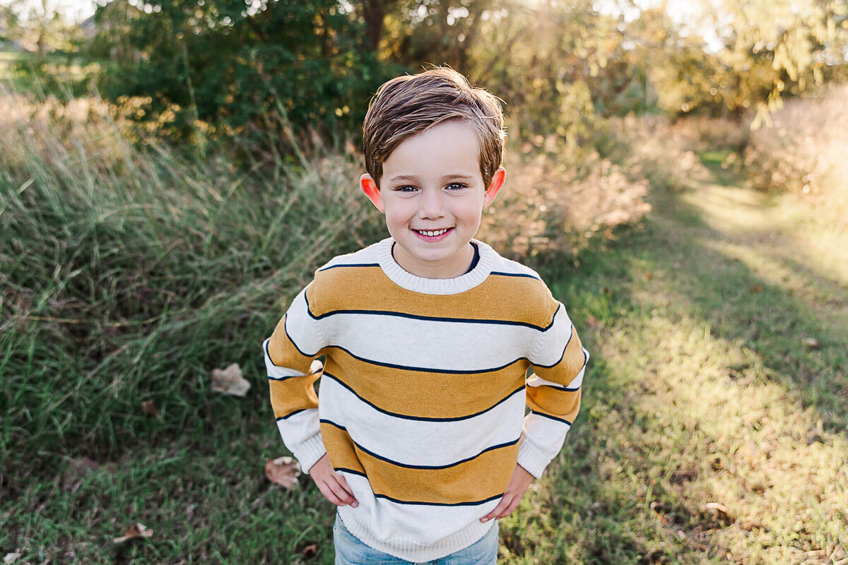 Boy smiling at the camera wearing yellow and white stripes