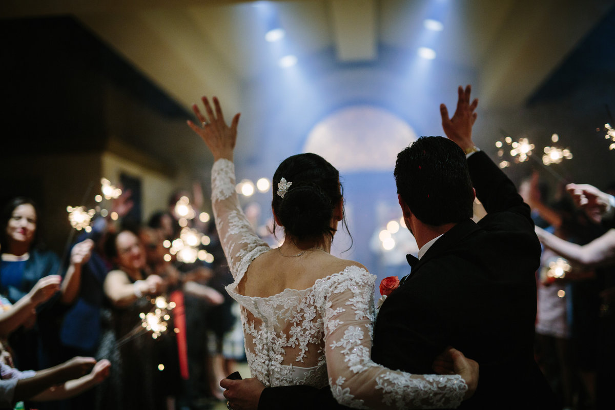 bride and groom wave to guests as they exit wedding reception at Club at Sonterra venue in San Antonio