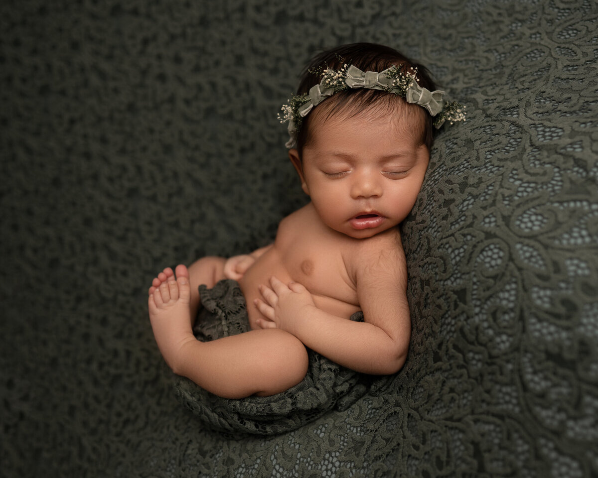 newborn girl sleeping on sage green floral blanket