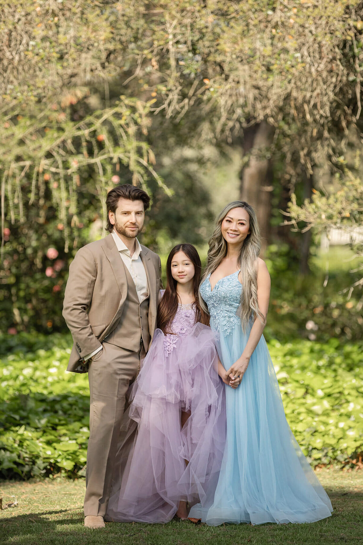 family of three photographed at LA arboretum in beautiful gowns and suit