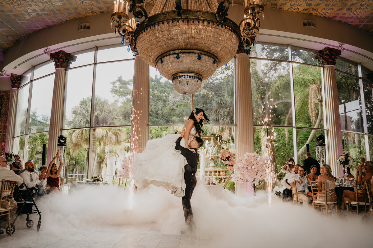 groom lifting bride during first dance with fog machine and cold sparks at kapok tree clearwater florida