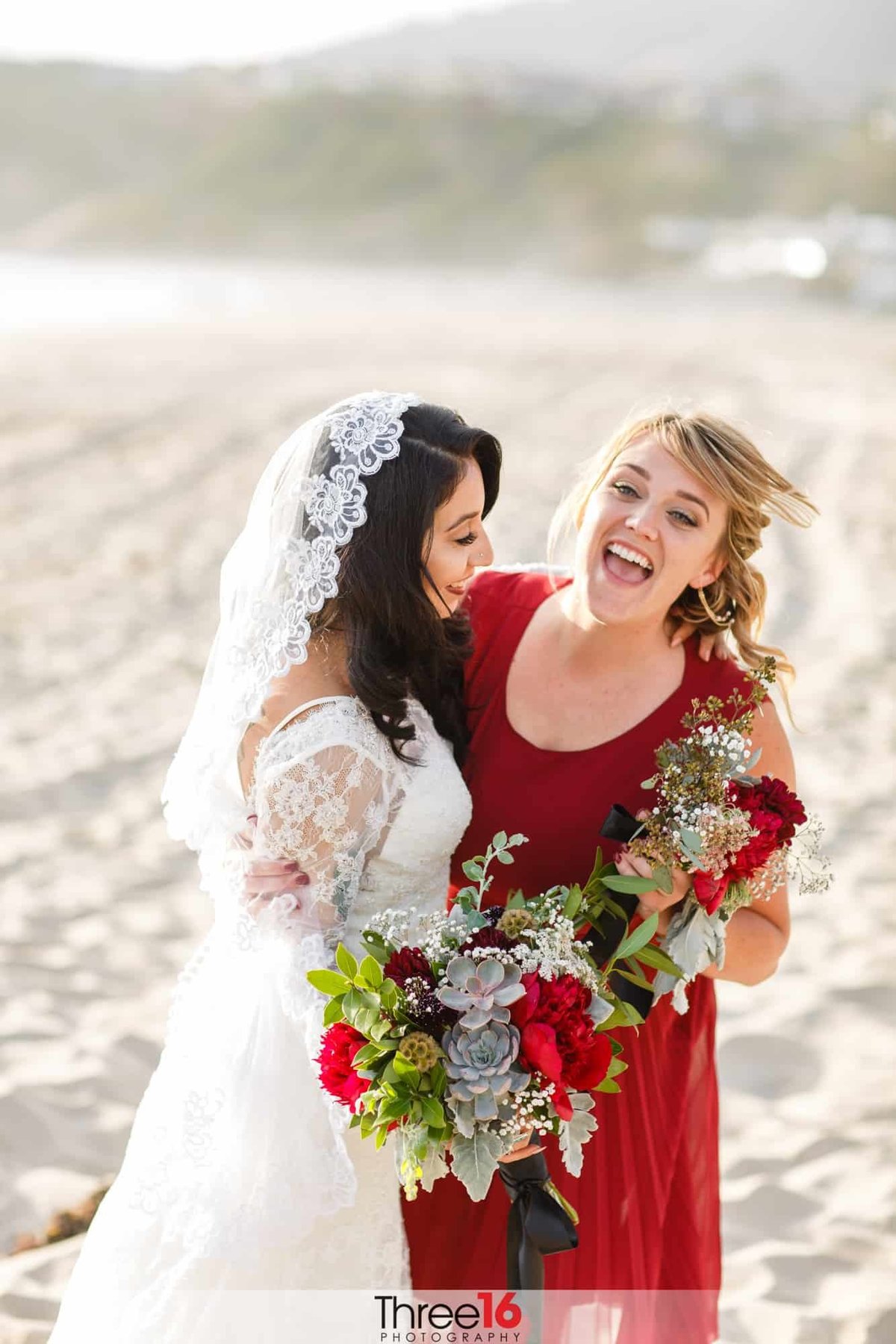 Bride shares a light moment with one of her Bridesmaids that is dressed in red