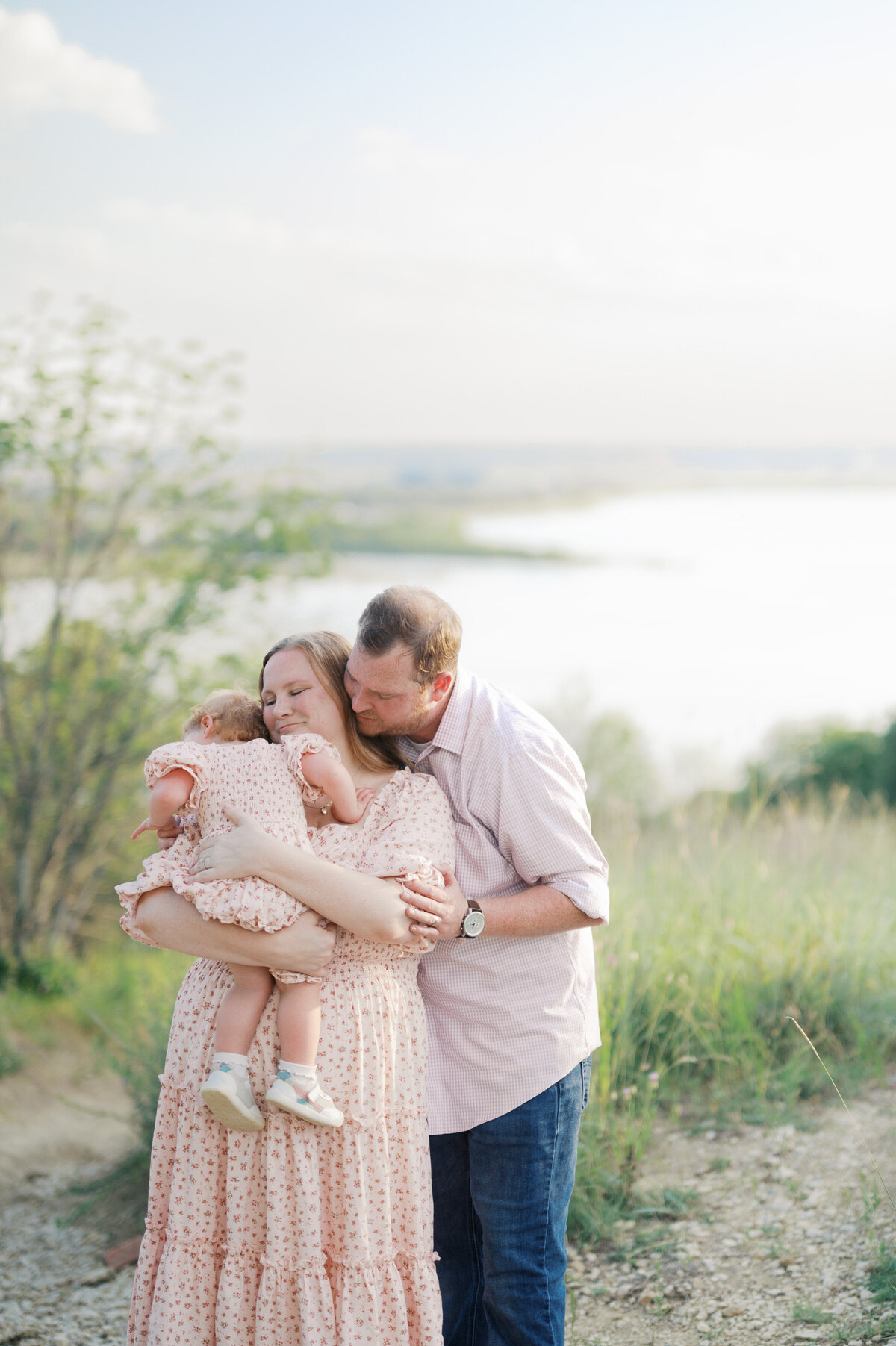 family of three snuggles close outdoors during family photos