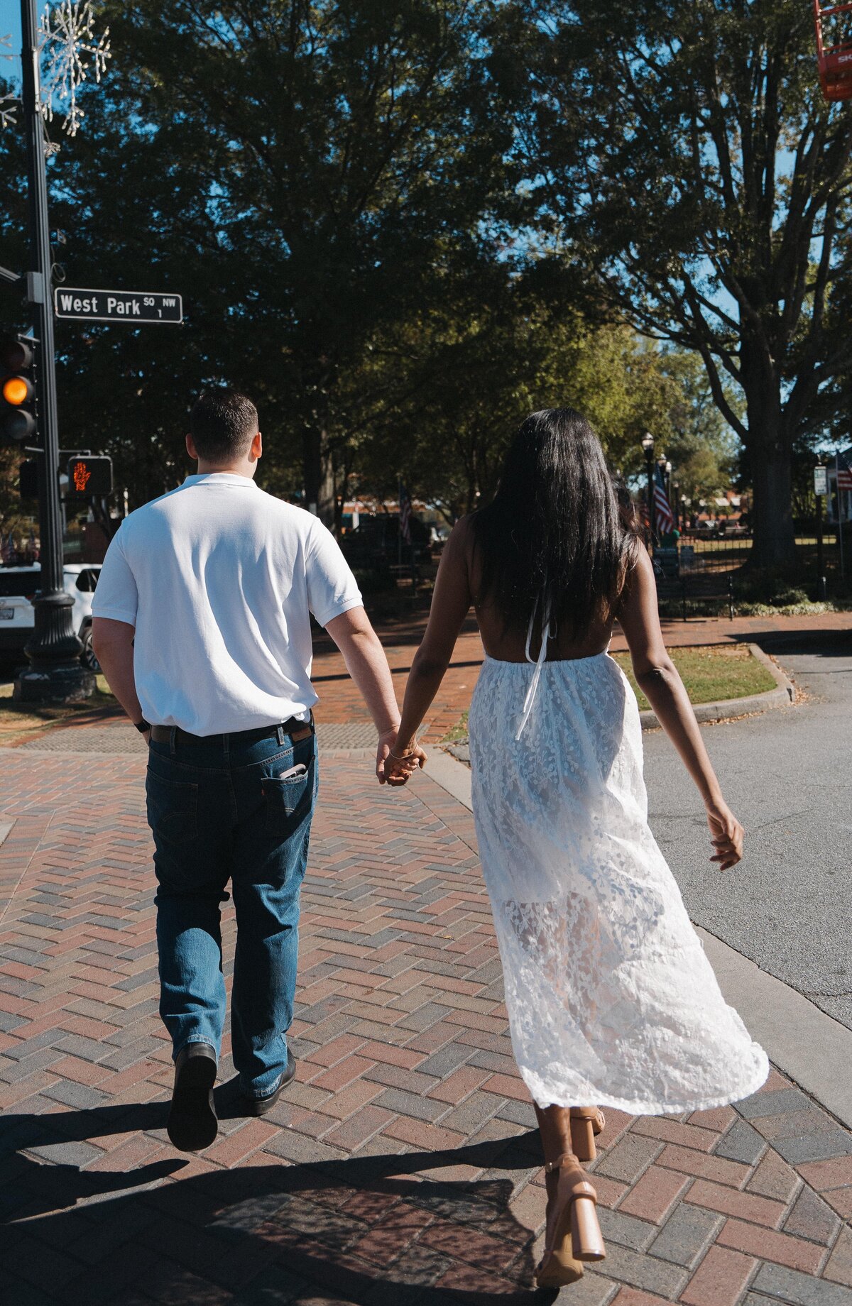 Couple holding hands while walking down a city street