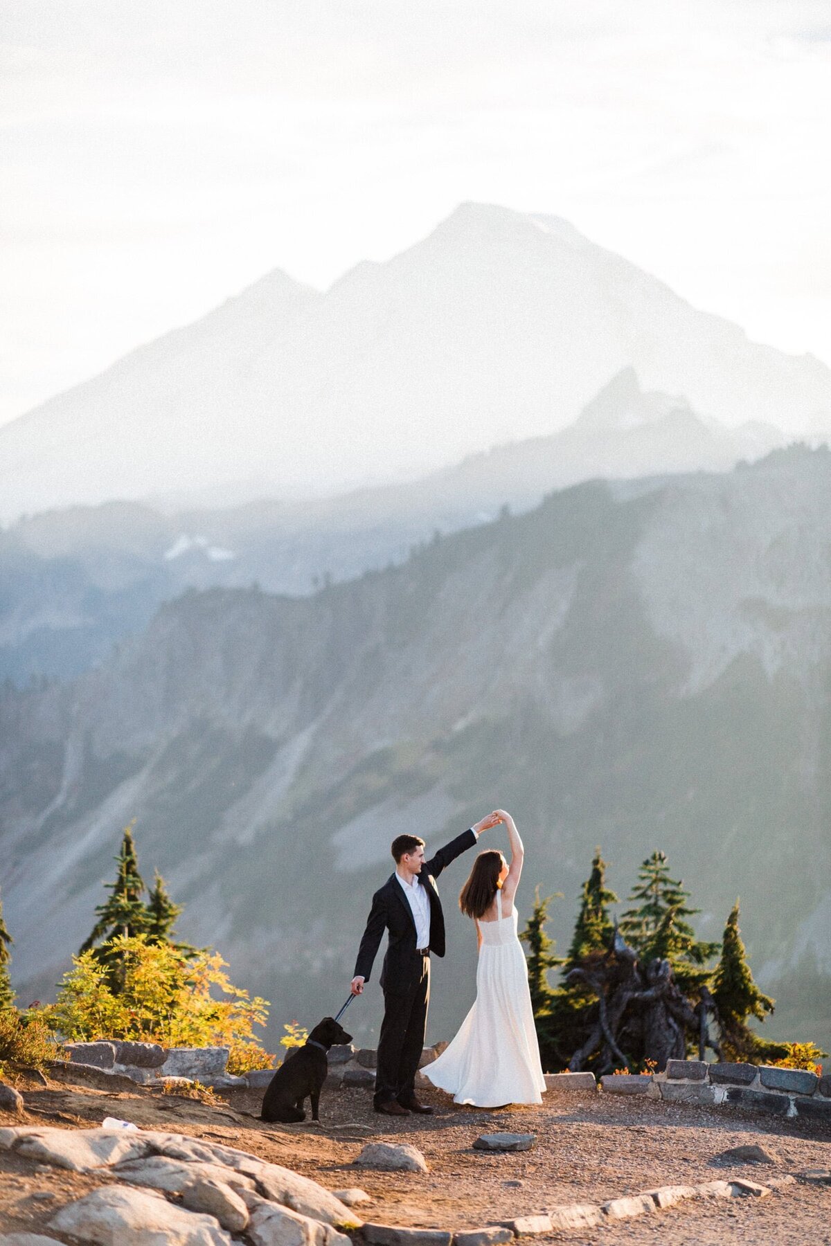 groom spinning bride below Mount Baker in the North Cascades at sunset. They also have a dog!