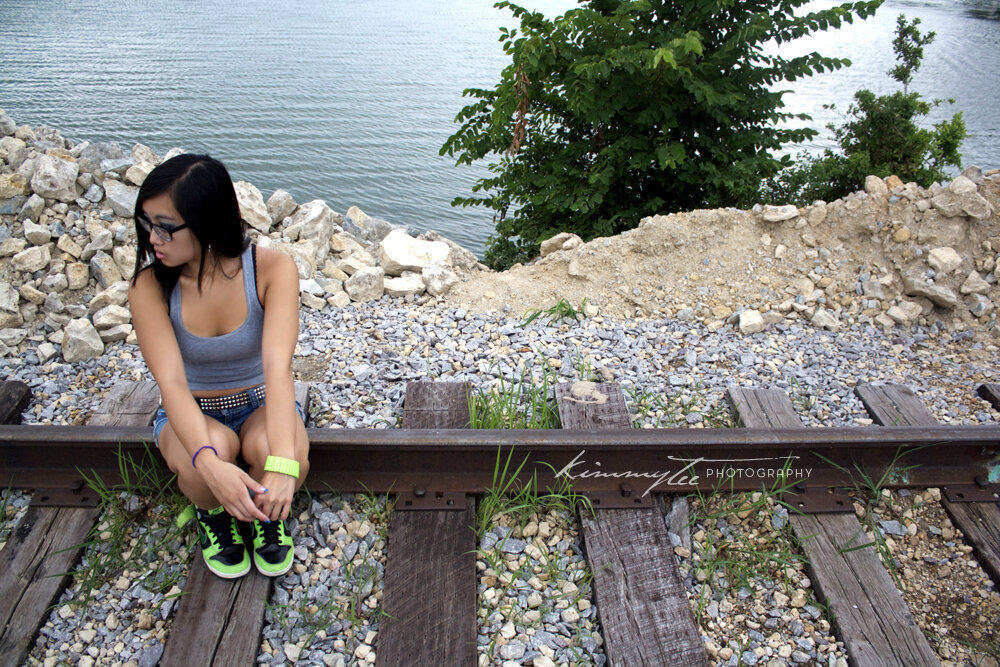 Girl sitting on railroad tracks near lake