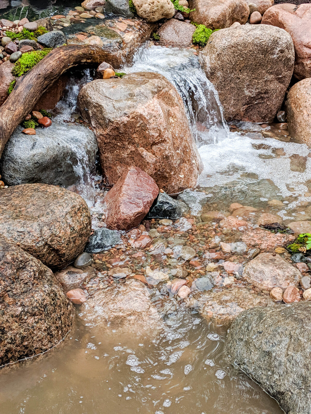 Flowing waterfall decorated with driftwood and moss