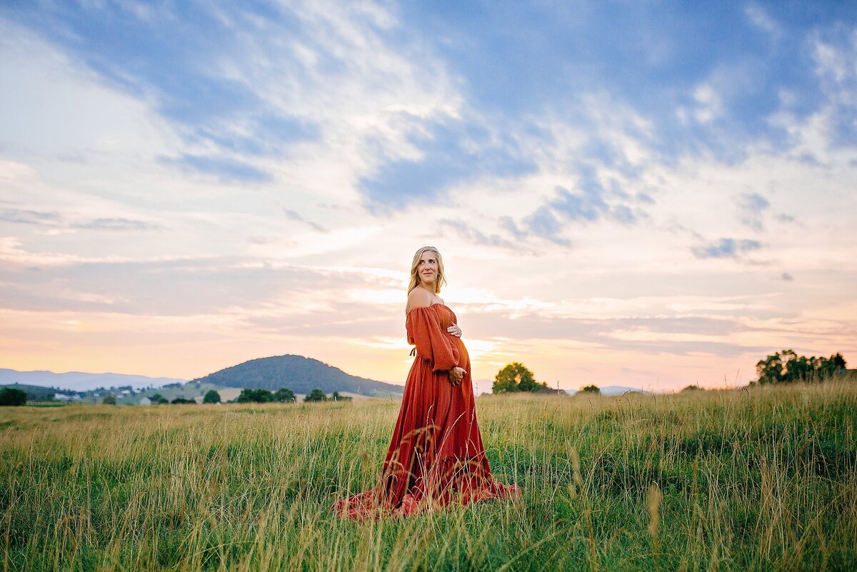 Maternity session in Harrisonburg.  Mom in red dress in a field at sunset