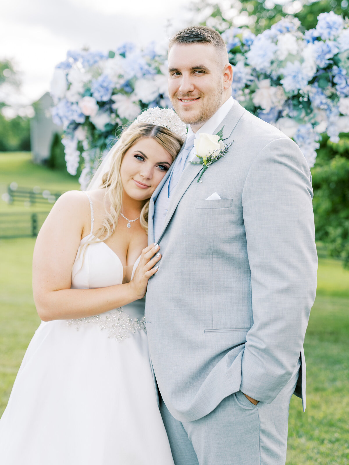 wedding image of couple in front of arbor as they look at the camera