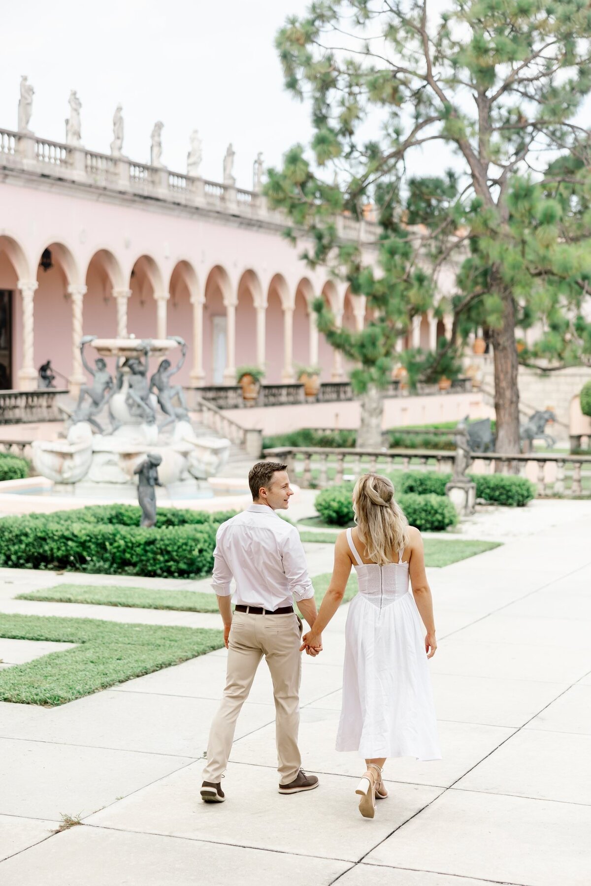 couple holding hands and walking away by wedding photographers fort myers