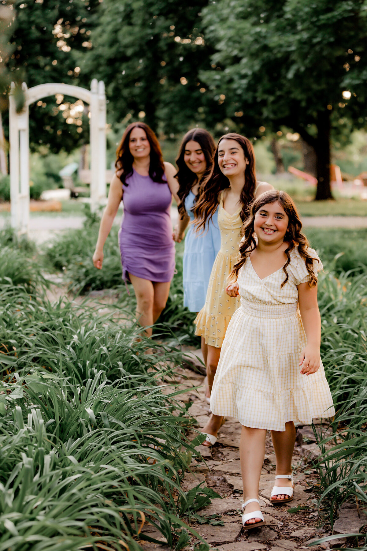 A girl and her family hold hands while she leads them through a path.