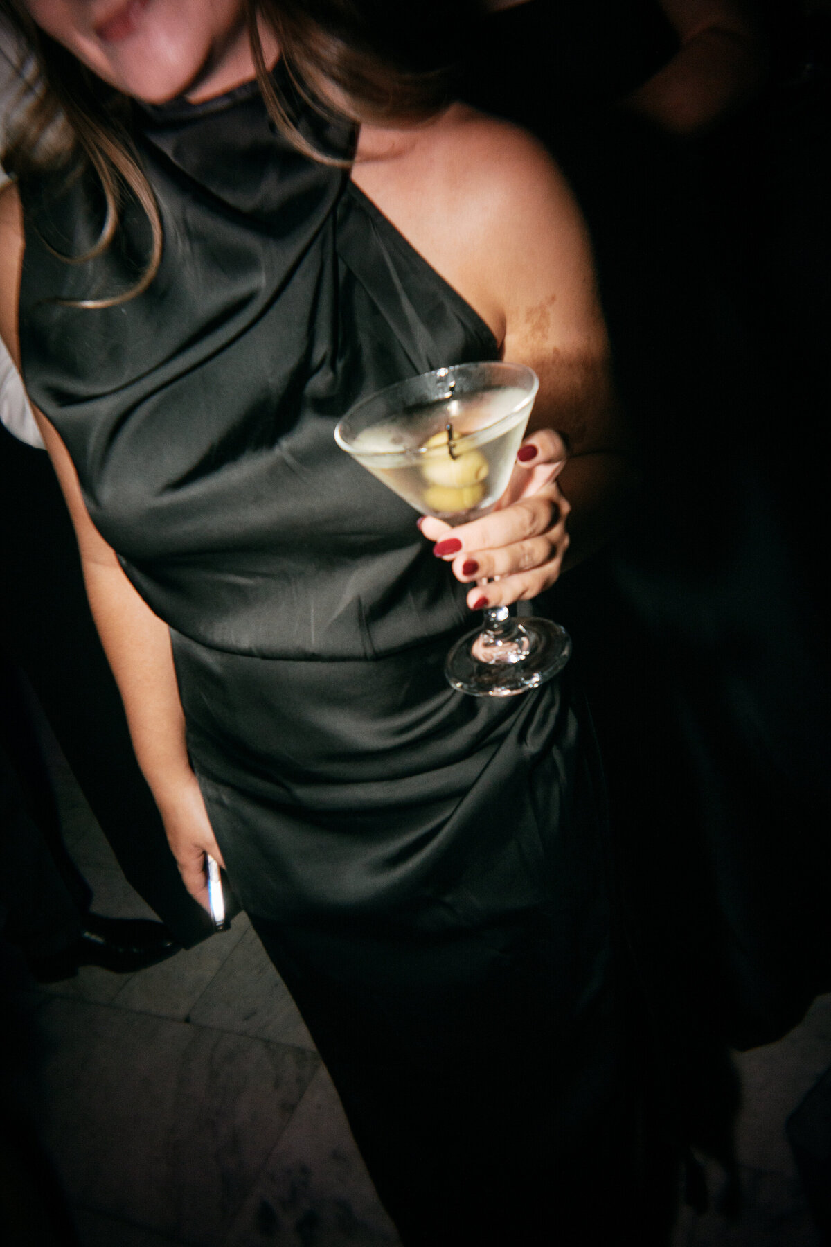 Wedding guest in black dress holding a martini at elegant Philly reception, captured by wedding photographer.