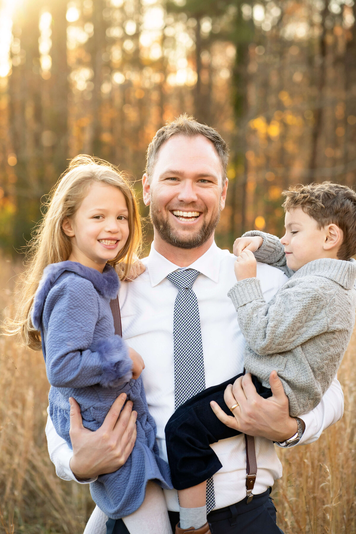 Dad smiling at camera while he holds son and daughter