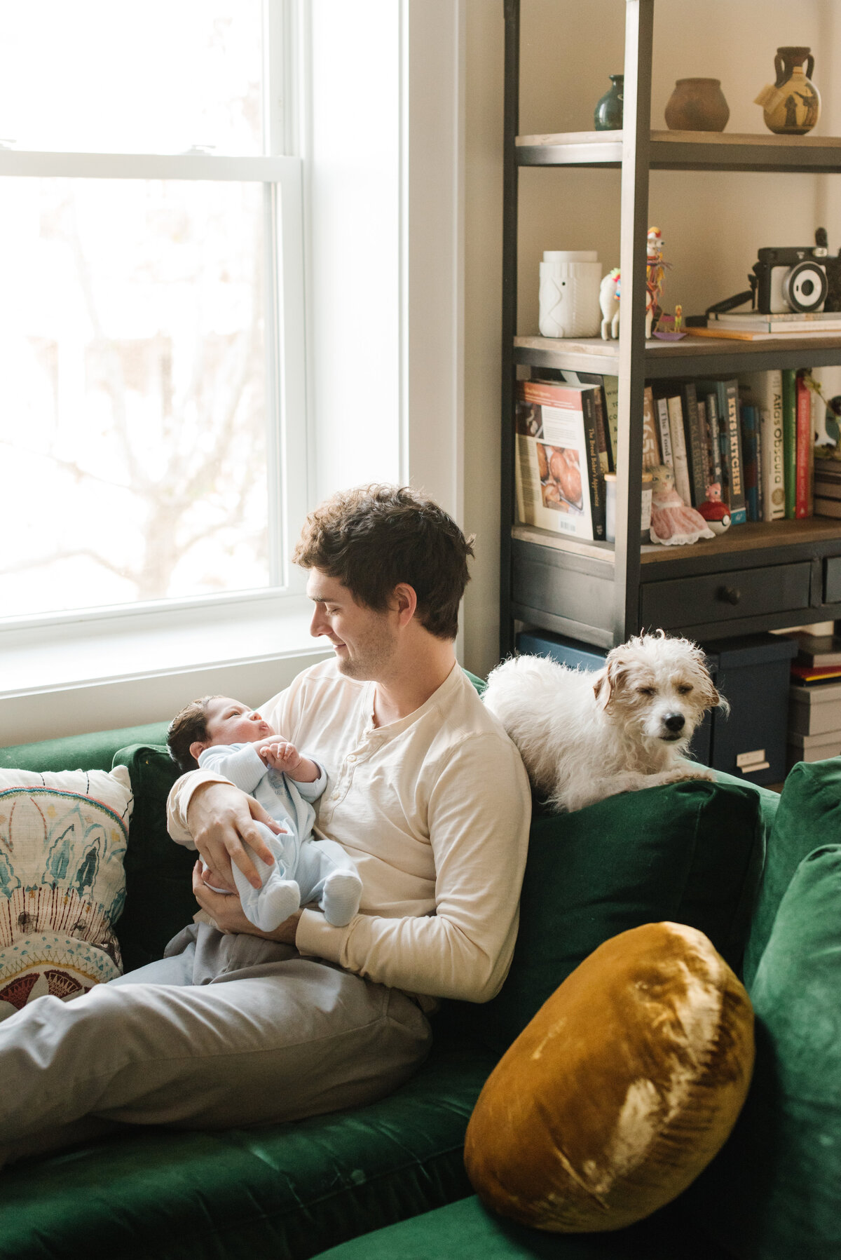Father with his baby and family dog on green couch