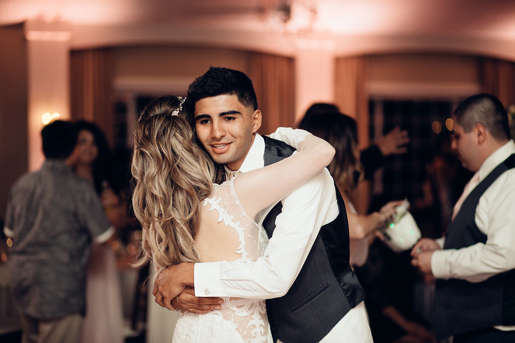 Wedding Photograph Of Man In Gray And White Suit Hugging The Bride Los Angeles