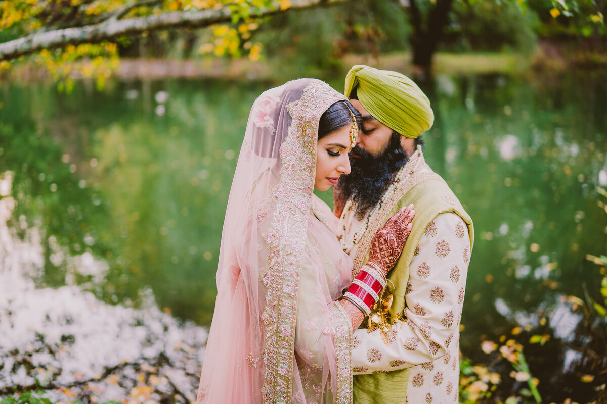 A sikh bride and groom together on their wedding day at the thielke arboretum in glen rock nj overlooking a pond